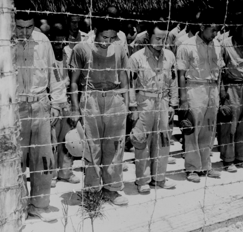 Japanese POW's at Guam, with bowed heads after hearing Emperor Hirohito make announcement of Japan's unconditional surrender." August 15, 1945.